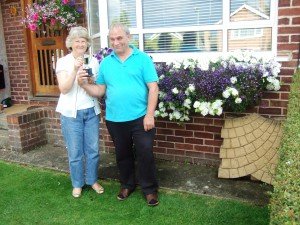 Couple holding silver cup, standing in front of prize windowbox