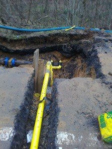 Yellow pipes and valves exposed below the surface of the road